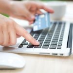 Hands holding a credit card and using laptop computer for online shopping